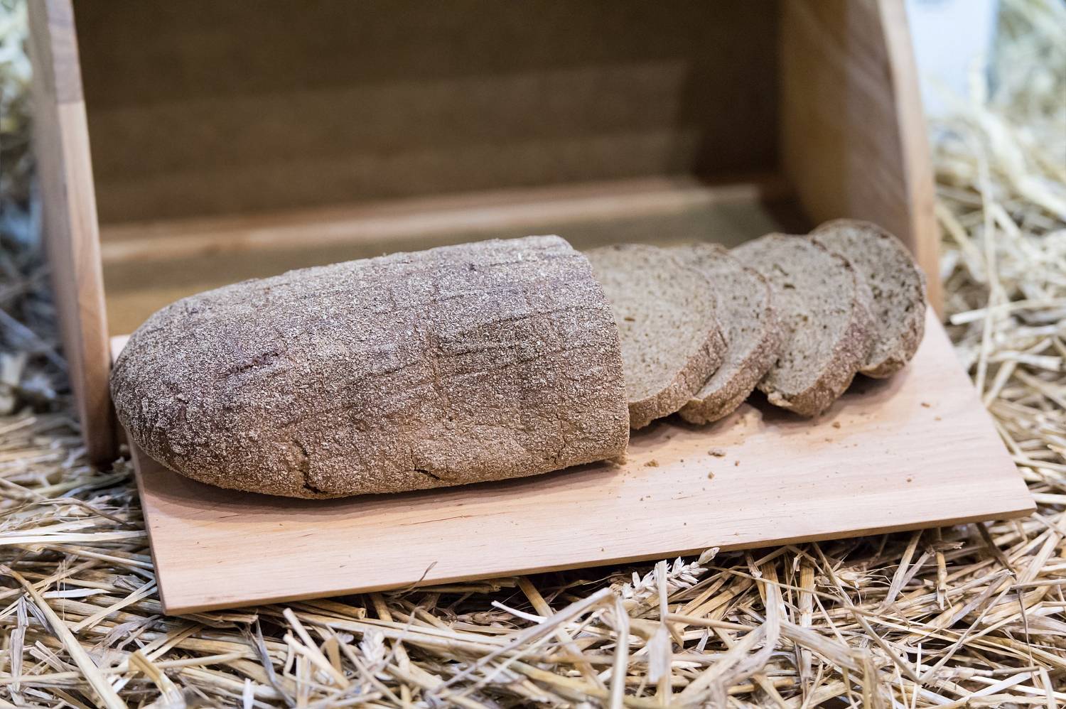 Pokrojony chleb leży w drewnianym chlebaku